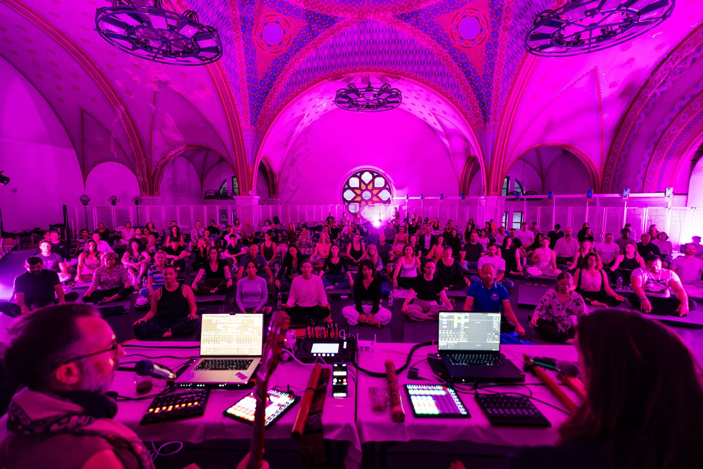 The Dózsa György Synagogue in Budapest glowing pink with the audience seated on mats